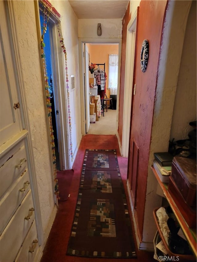 hall with dark colored carpet