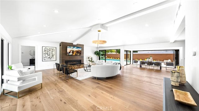 living room featuring a large fireplace, light wood-type flooring, and vaulted ceiling with beams