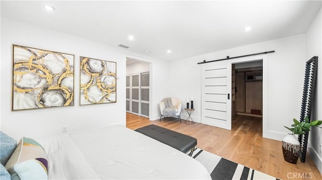 bedroom featuring a barn door and light hardwood / wood-style floors