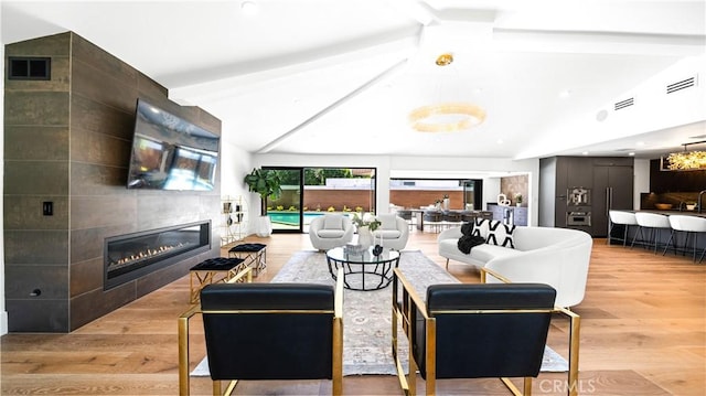 living room featuring vaulted ceiling with beams, a fireplace, and light hardwood / wood-style floors