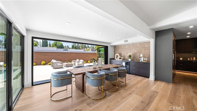 interior space featuring vaulted ceiling, wine cooler, light hardwood / wood-style floors, and butcher block counters