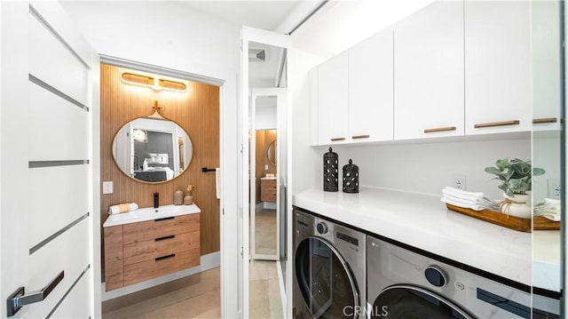 clothes washing area featuring cabinets and independent washer and dryer