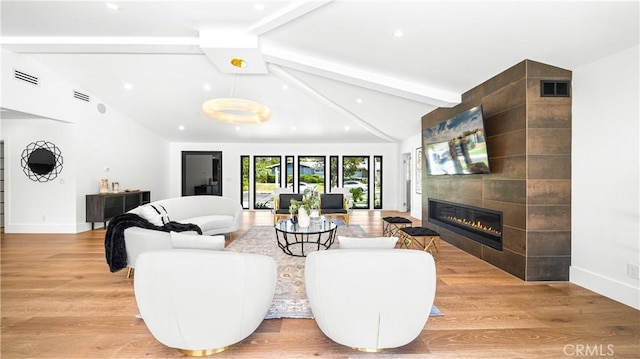 living room featuring light hardwood / wood-style floors, a fireplace, and lofted ceiling with beams