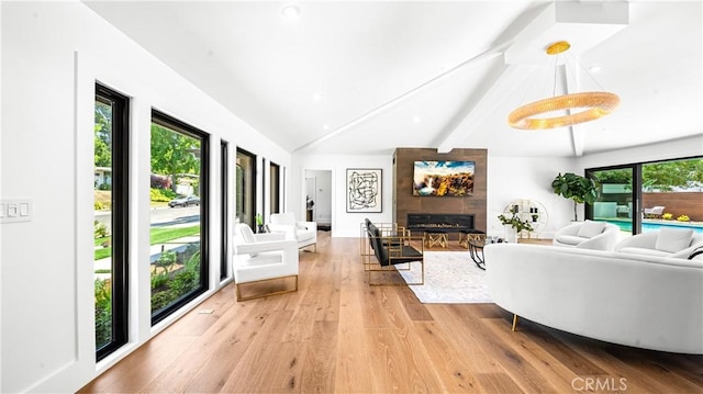 living room featuring a wealth of natural light, a large fireplace, wood-type flooring, and vaulted ceiling with beams