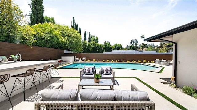 view of pool with a bar, an outdoor living space, and a patio