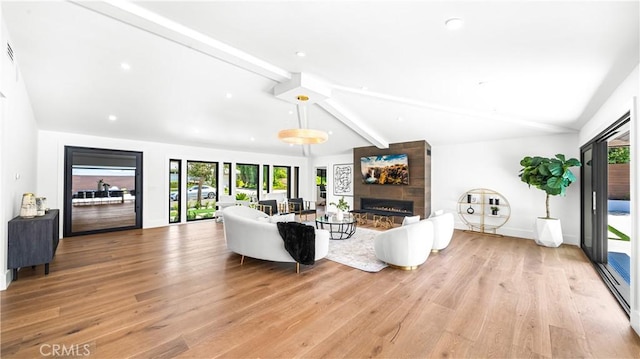 living room featuring plenty of natural light, a fireplace, and vaulted ceiling with beams