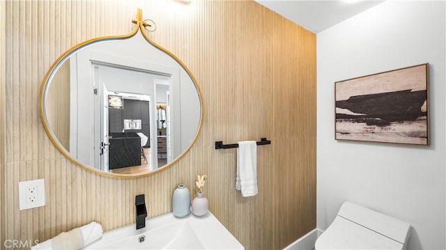 bathroom featuring sink, toilet, and wooden walls