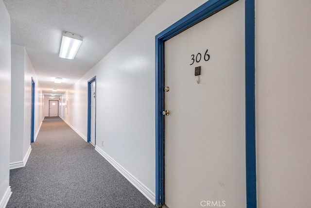 hall featuring a textured ceiling and carpet flooring