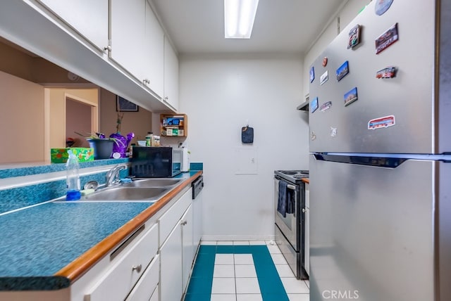 kitchen featuring light tile patterned floors, appliances with stainless steel finishes, sink, and white cabinetry