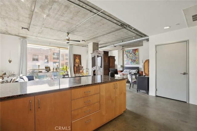 kitchen featuring ceiling fan and dark stone countertops