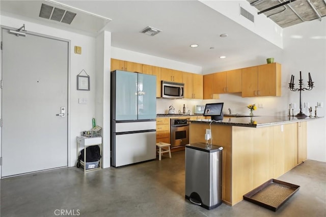 kitchen featuring sink, appliances with stainless steel finishes, kitchen peninsula, and dark stone countertops