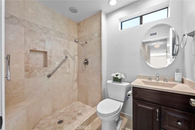 bathroom featuring a tile shower, vanity, and toilet