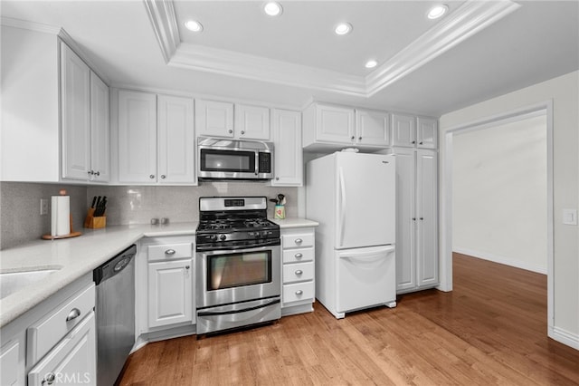 kitchen with a tray ceiling, white cabinetry, tasteful backsplash, and appliances with stainless steel finishes