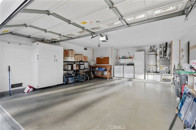 garage with strapped water heater, separate washer and dryer, and a garage door opener