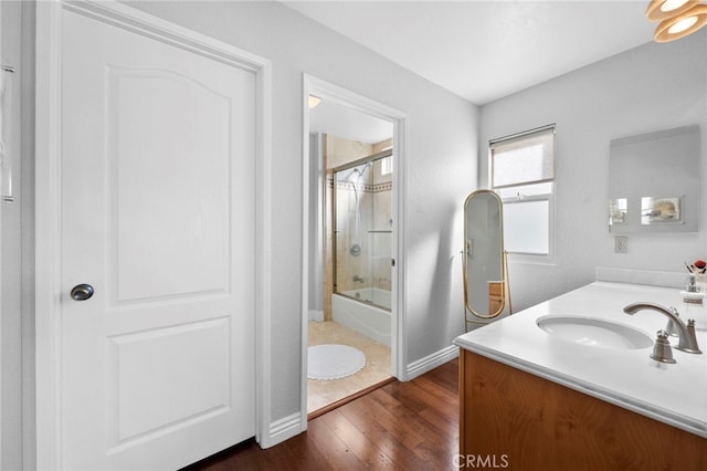 bathroom featuring vanity, hardwood / wood-style flooring, and enclosed tub / shower combo