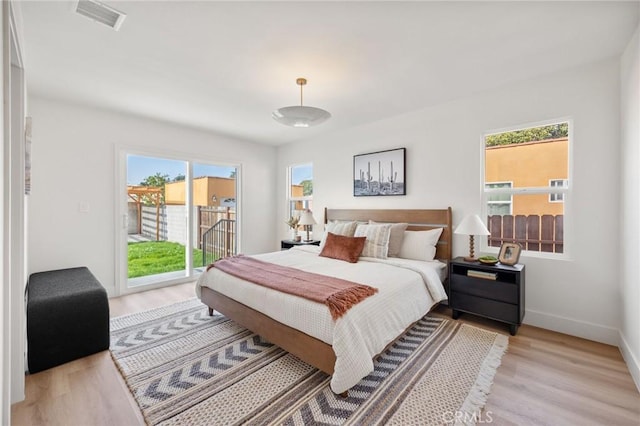 bedroom featuring access to exterior, light hardwood / wood-style flooring, and multiple windows