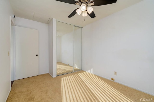 unfurnished bedroom with ceiling fan, light colored carpet, and a closet