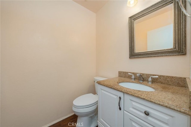 bathroom with hardwood / wood-style flooring, toilet, and vanity