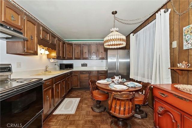 kitchen with hanging light fixtures, sink, appliances with stainless steel finishes, and dark parquet flooring