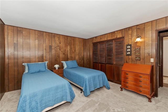 bedroom with light colored carpet, a closet, and wooden walls