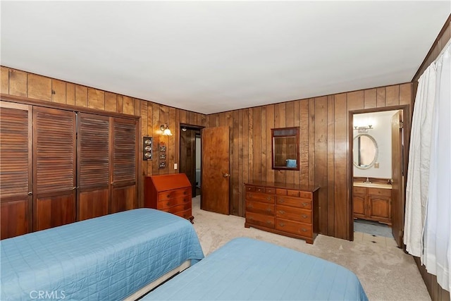 carpeted bedroom with a closet, wood walls, and connected bathroom