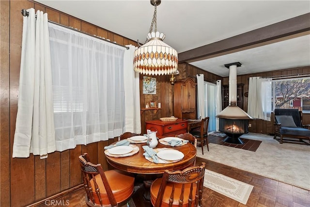 dining room with dark parquet floors, wood walls, and a wood stove