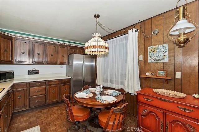 kitchen with dark parquet floors, wooden walls, stainless steel appliances, and pendant lighting