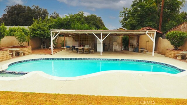 view of swimming pool with a pool with connected hot tub, a patio area, and a fenced backyard