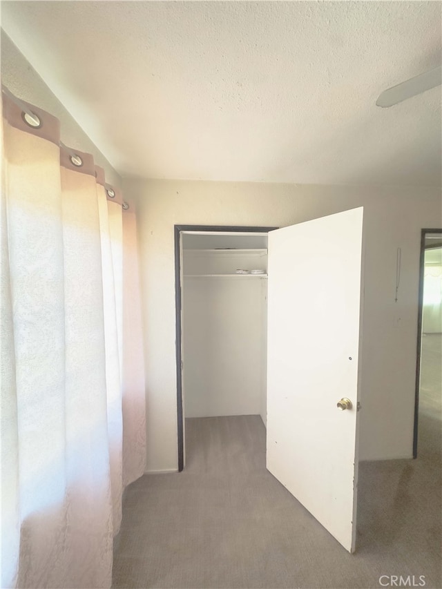 hallway with dark carpet and a textured ceiling