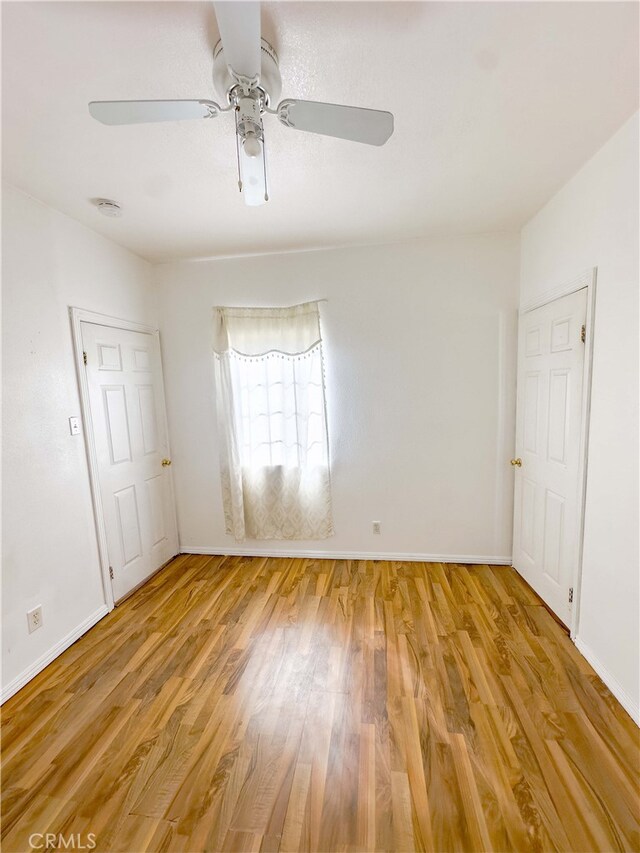 interior space with light wood-style floors, baseboards, and a ceiling fan