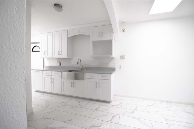 kitchen with marble finish floor, light countertops, and white cabinetry