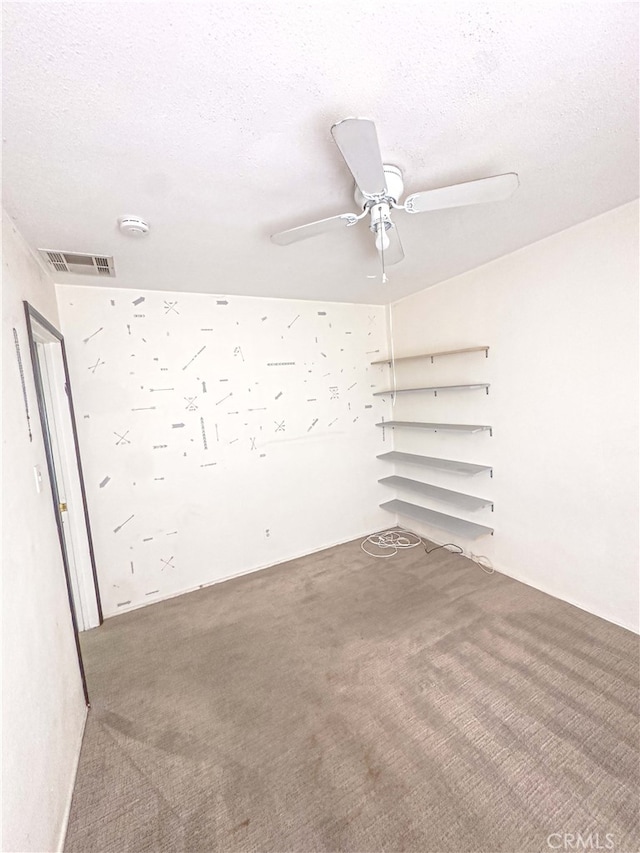 carpeted empty room featuring ceiling fan, visible vents, and a textured ceiling