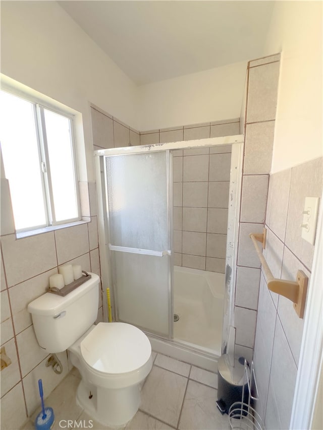 full bathroom featuring toilet, a shower stall, and tile walls