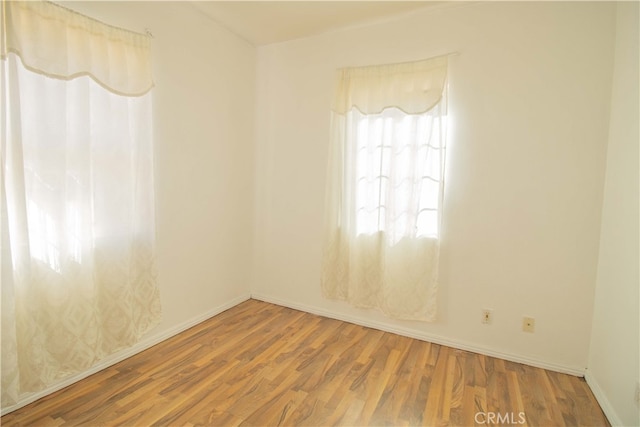 spare room featuring baseboards and wood finished floors