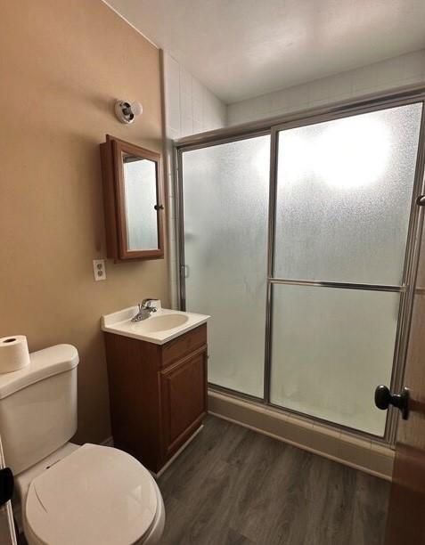 bathroom featuring hardwood / wood-style floors, toilet, walk in shower, and vanity