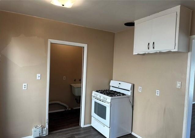 kitchen featuring white cabinets, dark wood-type flooring, and white gas range