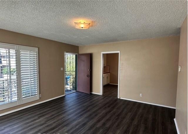 spare room with a textured ceiling and dark hardwood / wood-style flooring