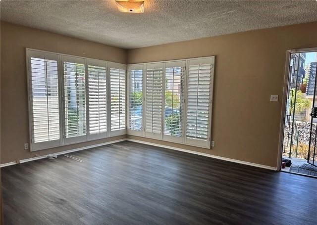 unfurnished room with a textured ceiling and dark hardwood / wood-style floors