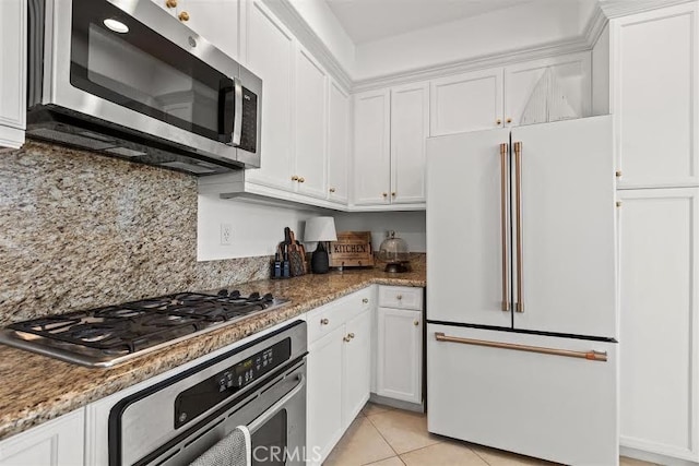 kitchen with appliances with stainless steel finishes, light tile patterned flooring, stone counters, and white cabinetry