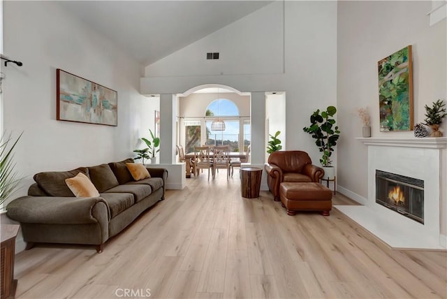 living room featuring high vaulted ceiling and light wood-type flooring