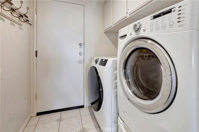 laundry room featuring washer and dryer, cabinets, and light tile patterned floors