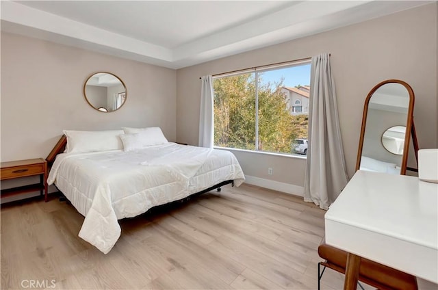 bedroom featuring light wood-type flooring and a tray ceiling