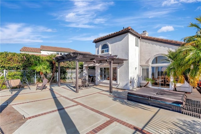 rear view of house with a covered hot tub, a pergola, and a patio