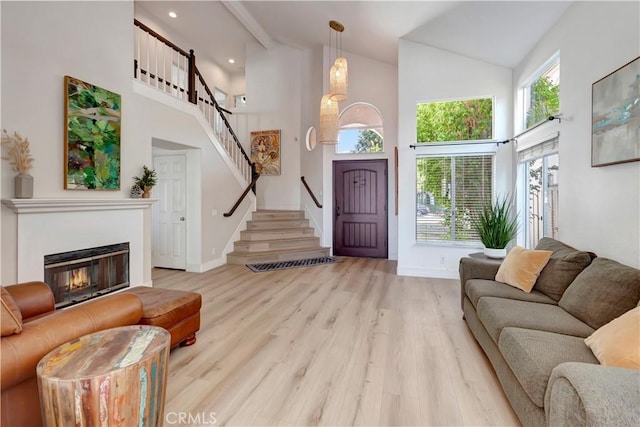 living room with light hardwood / wood-style floors and high vaulted ceiling