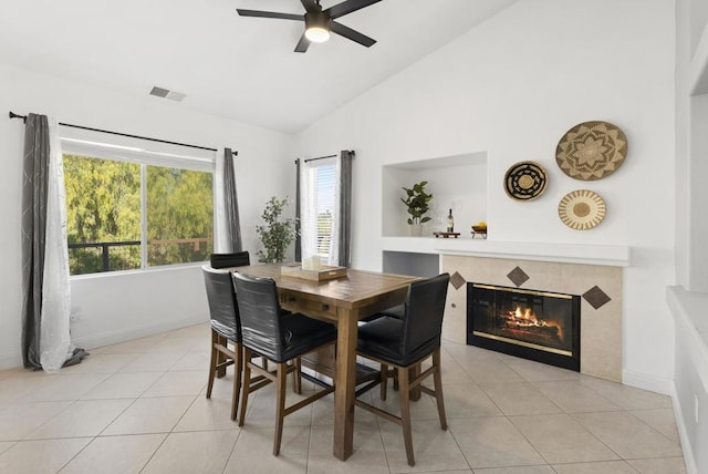 tiled dining room featuring ceiling fan, vaulted ceiling, and a tiled fireplace