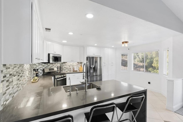 kitchen with white cabinetry, kitchen peninsula, a breakfast bar area, stainless steel appliances, and sink