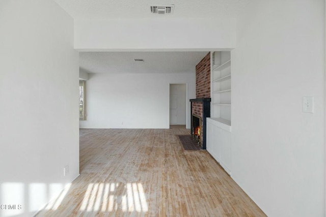 corridor with light hardwood / wood-style floors and built in shelves