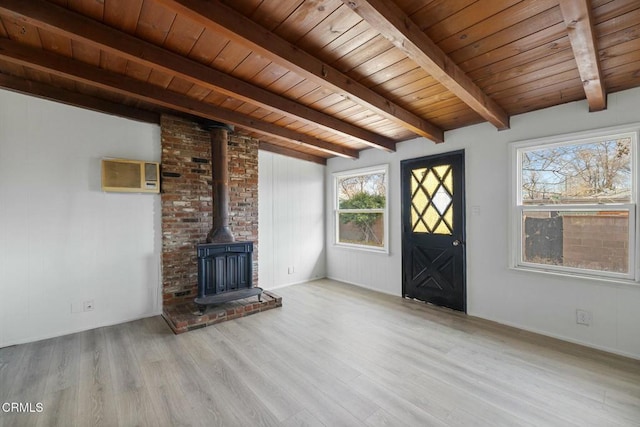 unfurnished living room featuring vaulted ceiling with beams, a wood stove, light hardwood / wood-style floors, and wooden ceiling