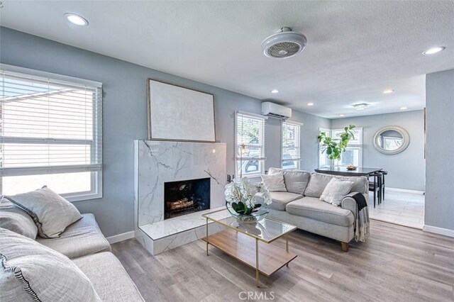 living room with a wall mounted AC, a high end fireplace, and wood-type flooring