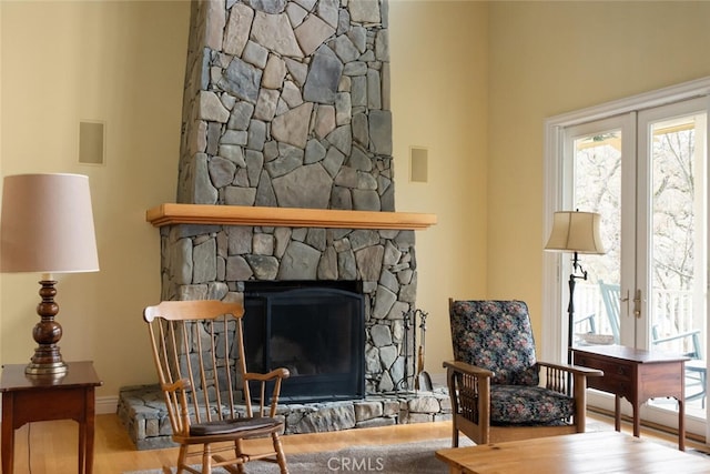 living room with french doors, hardwood / wood-style flooring, and a stone fireplace